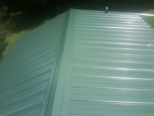 New green metal panels meeting at the ridge of a roof — Flat Roof Repair work by our crew in Williamstown